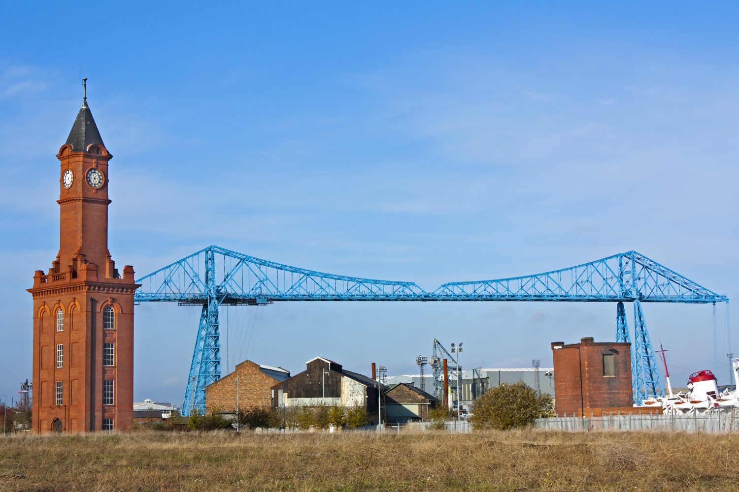 Landscape scene including a tower and blue industrial bridge.