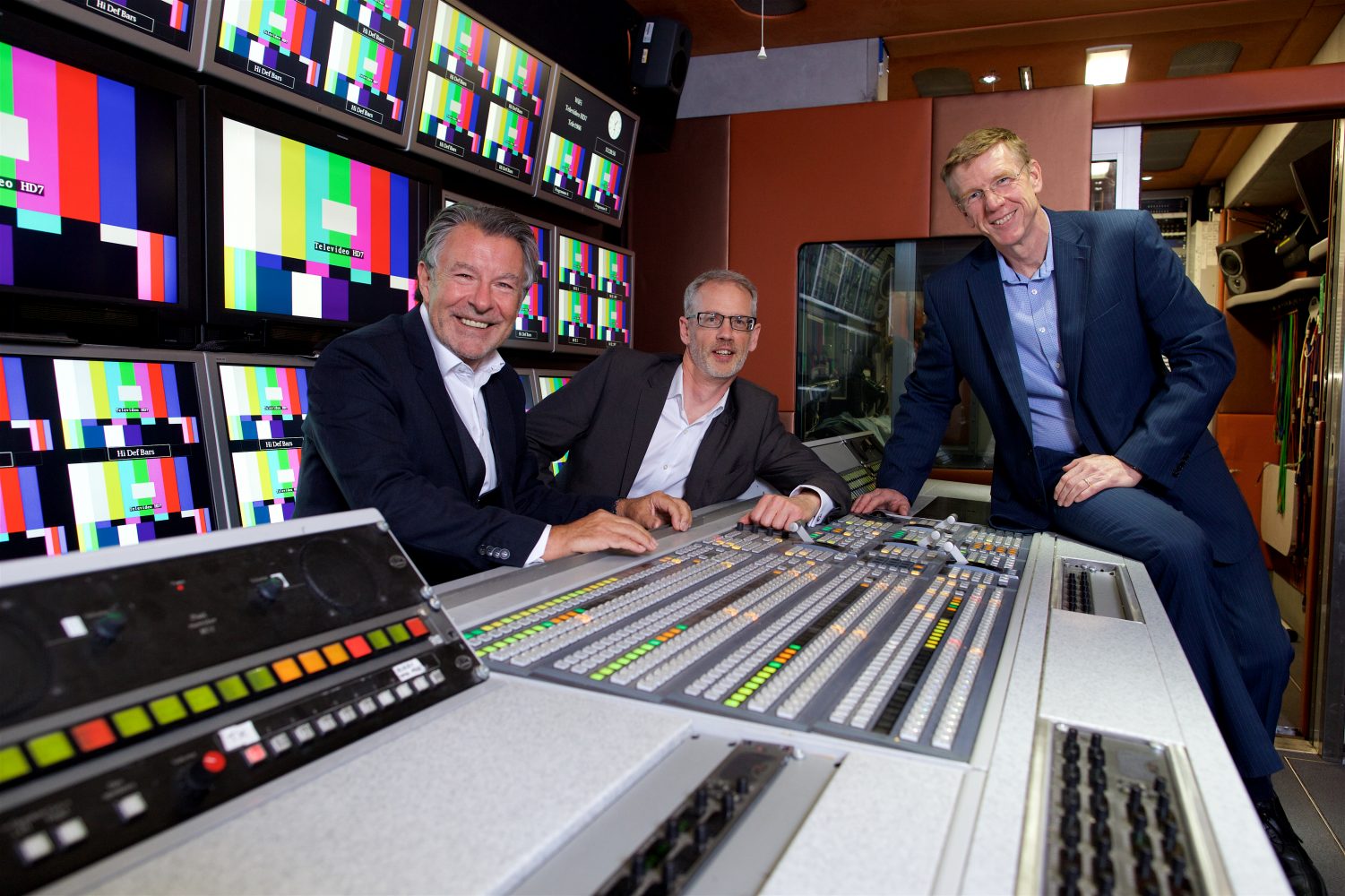 3 men in suits from Televido sat in a broadcasting room