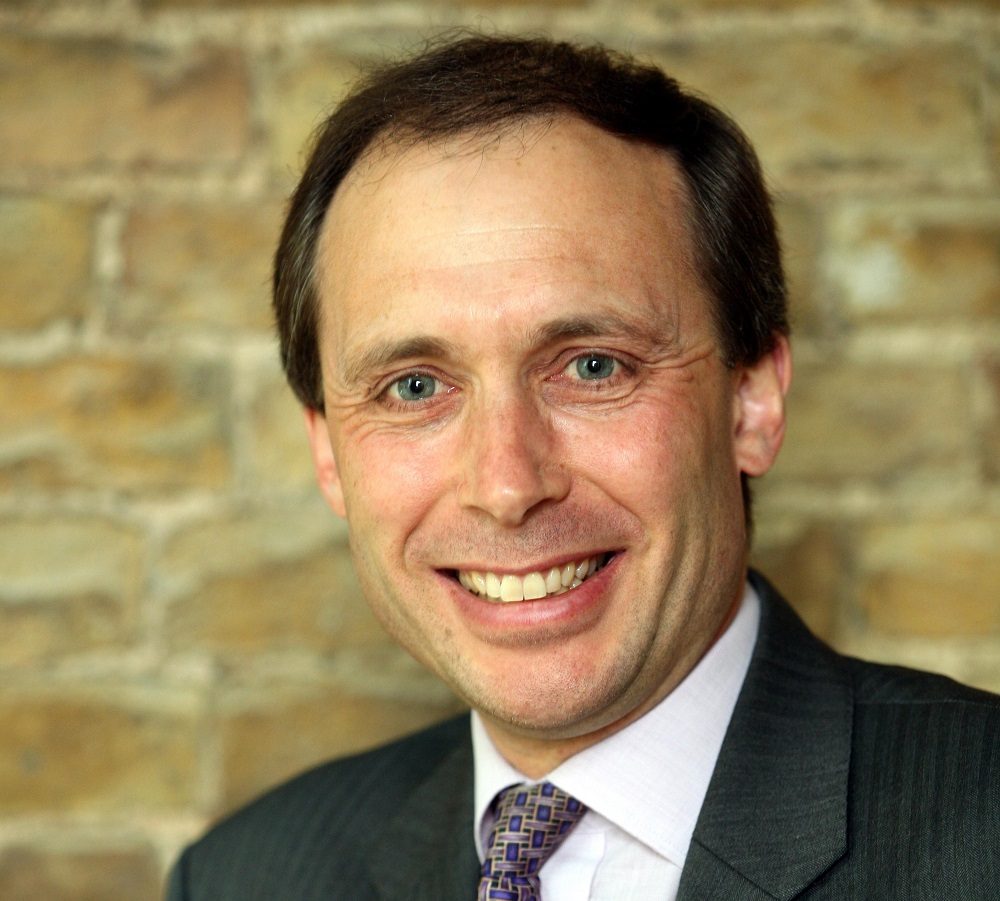 Headshot of man named Philip Cox. He is wearing a colourful tie.