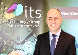 Man in suit in front of ITS Technology Group branding on the wall.