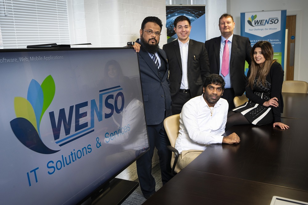 4 men and a woman sat in a meeting room with Wenso IT Solutions and Services TV Screen and pop up banner