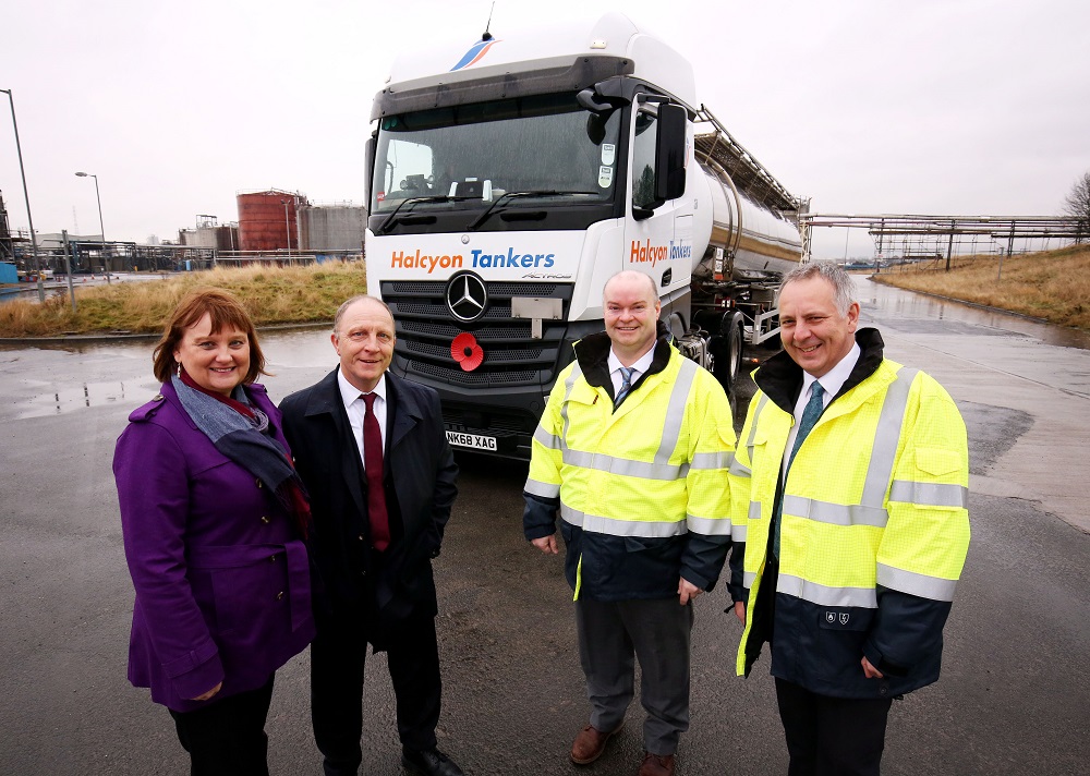 Two men standing outside wearing Hi Vis in front of Halcyon Tankers and a woman and man wearing casual clothing in front of the truck.