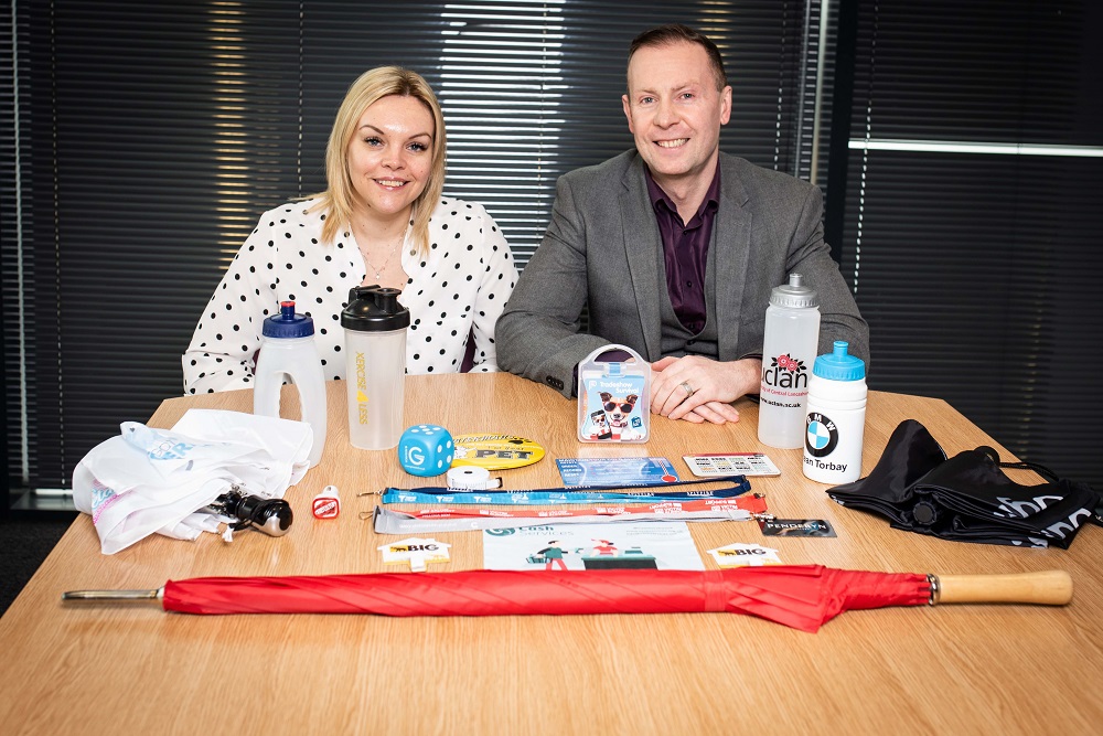 Man and woman sitting next to each other behind a desk surrounded by products.