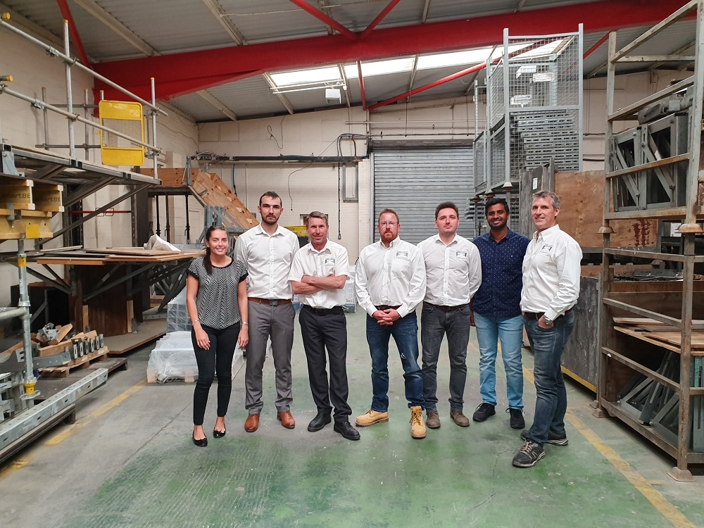 A group of employees from Fast Form stood in a warehouse smiling