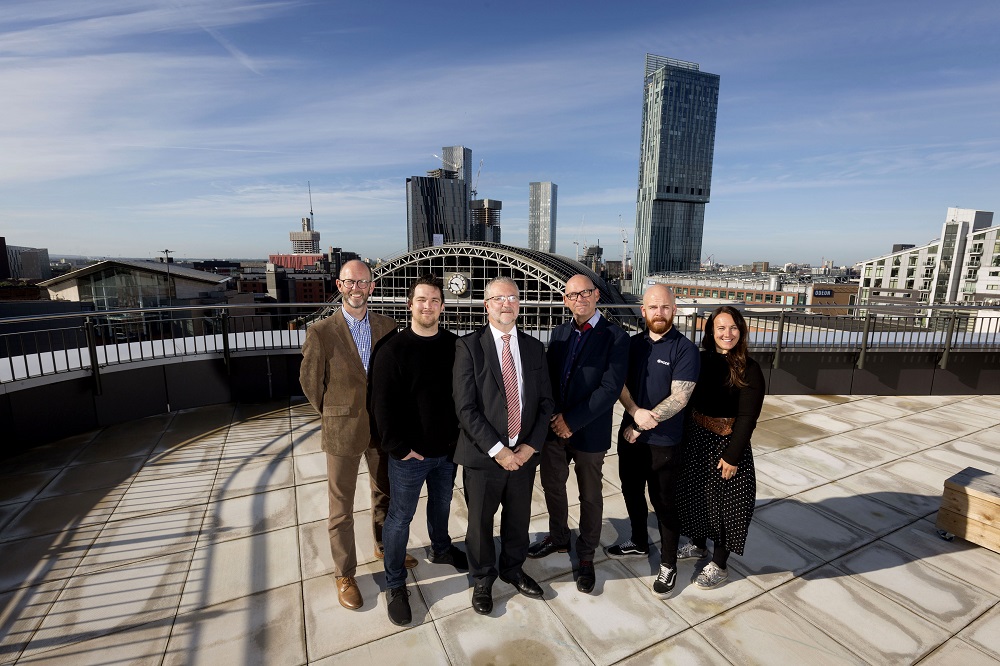 Employees from Node Technologies stood on a large balcony overlooking the city of Manchester