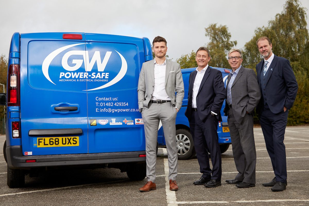 4 men in suits stood in a car park with 2 GW Power Safe vans