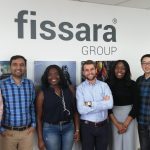 A group of employees stood in front of a Fissara group branded wall