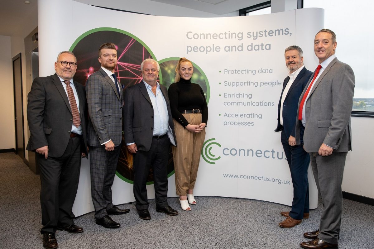 A group of employees from Connectus standing in front of a Connectus branded pop up banner